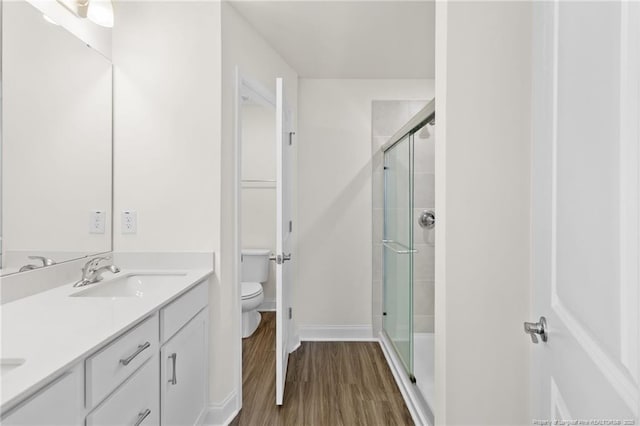 bathroom with a shower with door, vanity, hardwood / wood-style flooring, and toilet