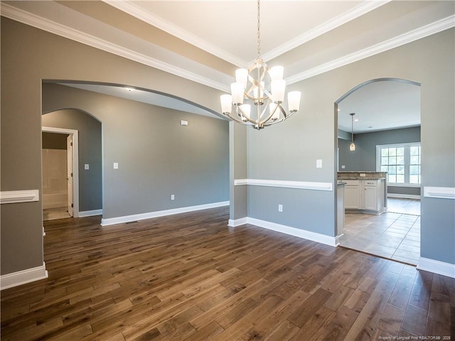 spare room with dark wood-type flooring, crown molding, and a chandelier