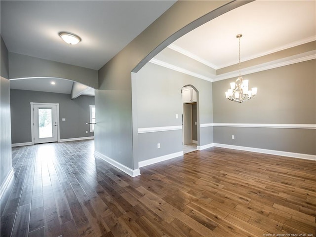 empty room with a notable chandelier, crown molding, and dark hardwood / wood-style flooring