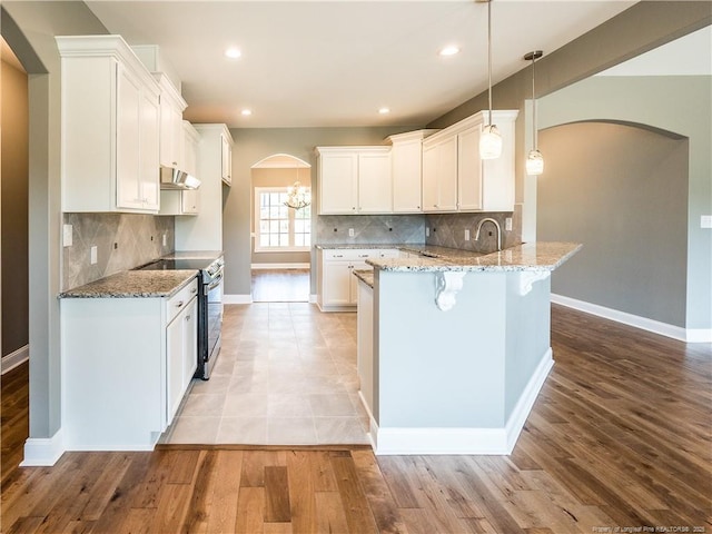 kitchen with white cabinets, pendant lighting, stainless steel range with electric cooktop, and light stone countertops