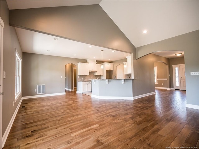 unfurnished living room featuring high vaulted ceiling and hardwood / wood-style flooring