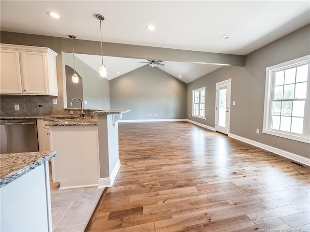 kitchen featuring dishwasher, lofted ceiling, stone counters, ceiling fan, and sink