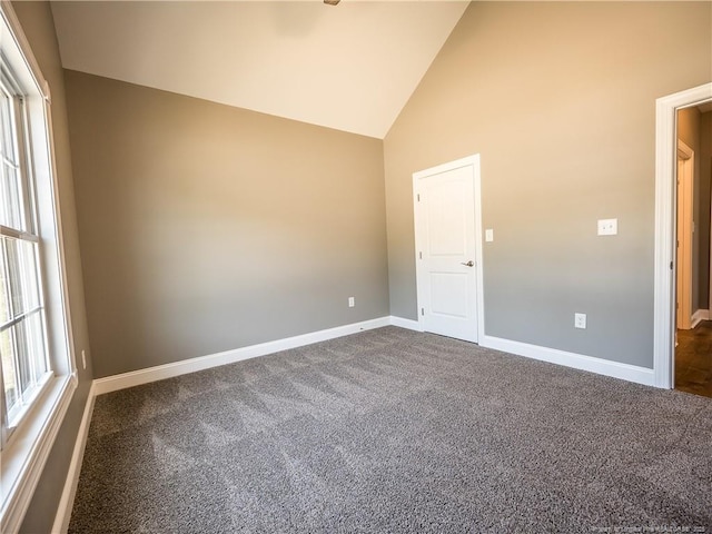 carpeted spare room with high vaulted ceiling