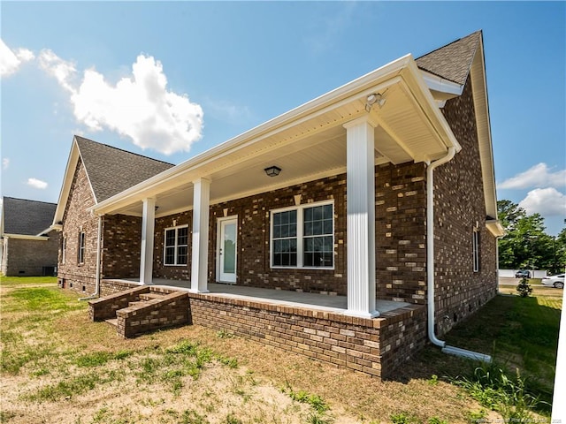 back of house with covered porch and a lawn