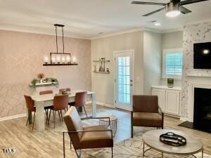 living room with light hardwood / wood-style floors, a large fireplace, ceiling fan, and crown molding