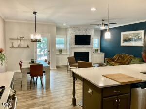 kitchen featuring a large fireplace, stainless steel appliances, ornamental molding, pendant lighting, and dark brown cabinets