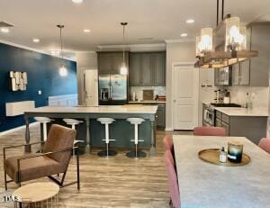 kitchen featuring decorative light fixtures, gray cabinets, and wall chimney exhaust hood