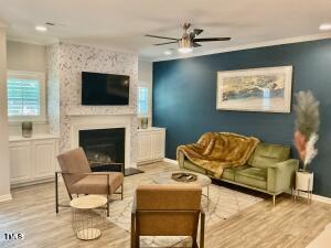 living room featuring a large fireplace, ceiling fan, and light hardwood / wood-style flooring