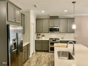 kitchen with sink, stainless steel appliances, ornamental molding, and hanging light fixtures