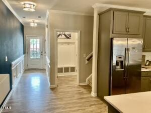 doorway to outside with ornamental molding and light wood-type flooring