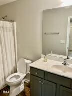 bathroom with toilet, a shower with shower curtain, and vanity