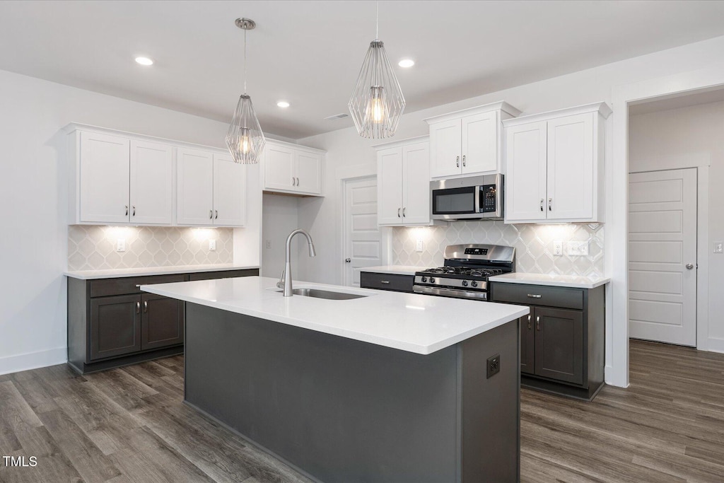 kitchen with a center island with sink, stainless steel appliances, white cabinetry, and sink