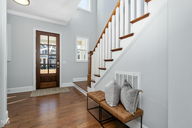 foyer entrance featuring a towering ceiling, dark hardwood / wood-style flooring, and crown molding