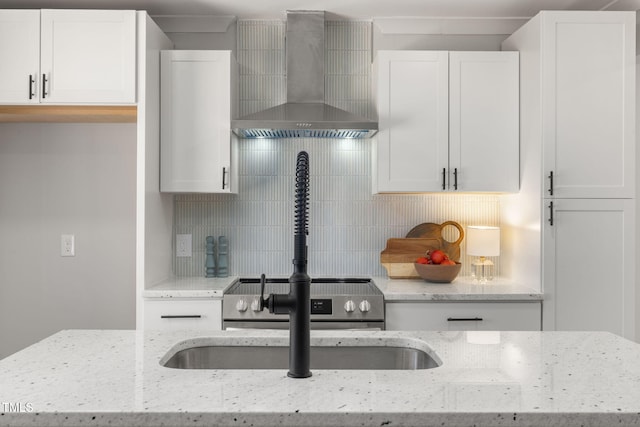 kitchen featuring white cabinets, wall chimney exhaust hood, and decorative backsplash