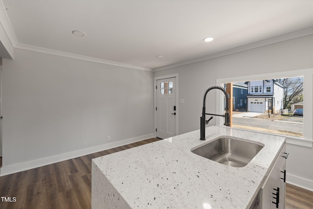 kitchen with sink, crown molding, a kitchen island with sink, and light stone counters