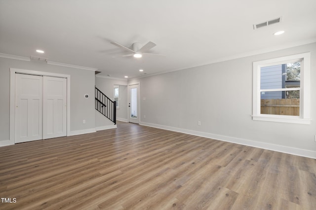 unfurnished living room with ceiling fan, wood-type flooring, ornamental molding, and plenty of natural light