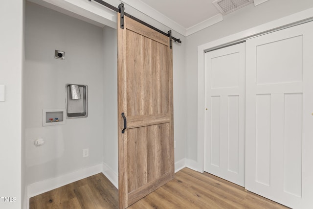 interior space with hookup for an electric dryer, hardwood / wood-style floors, a barn door, ornamental molding, and washer hookup