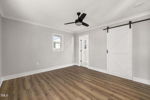 unfurnished bedroom with ceiling fan, crown molding, a barn door, and dark wood-type flooring