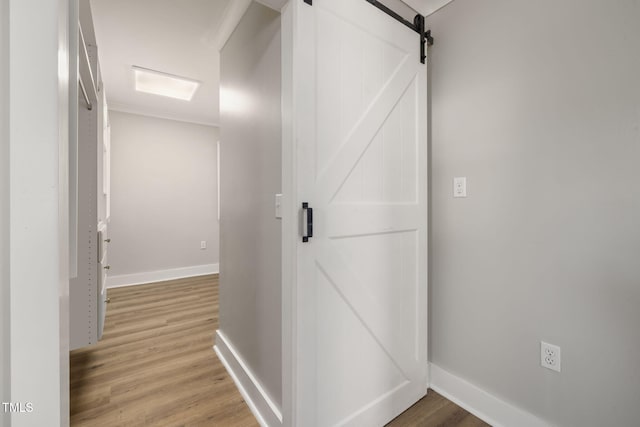 corridor featuring ornamental molding, hardwood / wood-style flooring, and a barn door