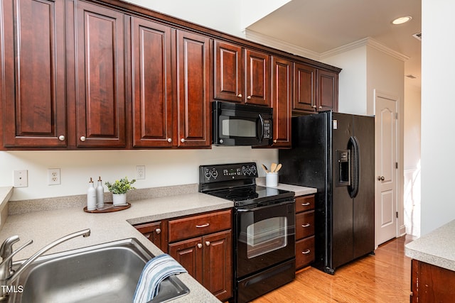 kitchen featuring crown molding, light hardwood / wood-style floors, black appliances, and sink