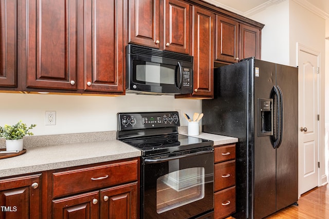 kitchen with light wood-type flooring, ornamental molding, and black appliances