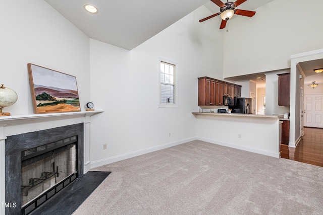 unfurnished living room featuring ceiling fan, high vaulted ceiling, and dark colored carpet