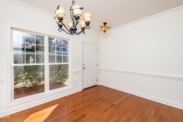 unfurnished dining area with ornamental molding, an inviting chandelier, hardwood / wood-style floors, and a wealth of natural light