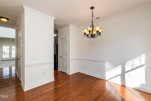 empty room with dark hardwood / wood-style flooring, ornamental molding, and a chandelier