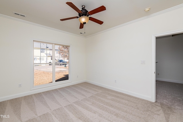 empty room featuring ceiling fan, crown molding, and light colored carpet