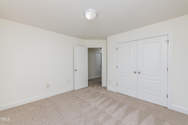 unfurnished bedroom with light colored carpet and a closet