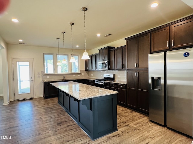 kitchen with pendant lighting, sink, a breakfast bar, stainless steel appliances, and a kitchen island