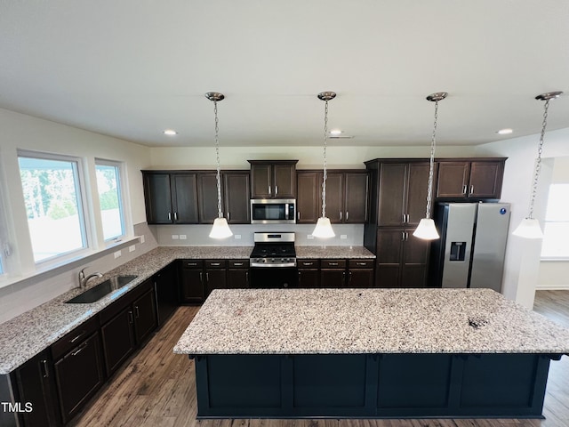 kitchen with hanging light fixtures, a center island, appliances with stainless steel finishes, and sink