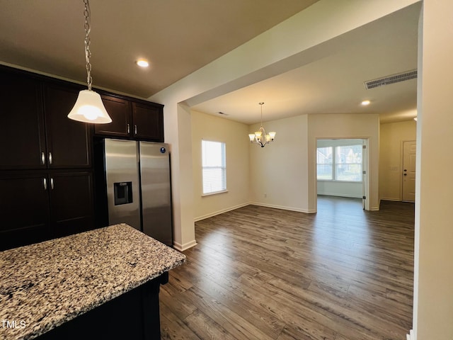 kitchen featuring stainless steel fridge with ice dispenser, decorative light fixtures, a wealth of natural light, and light stone countertops