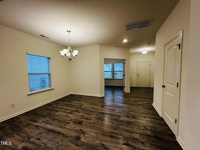 unfurnished dining area featuring an inviting chandelier and dark wood-type flooring