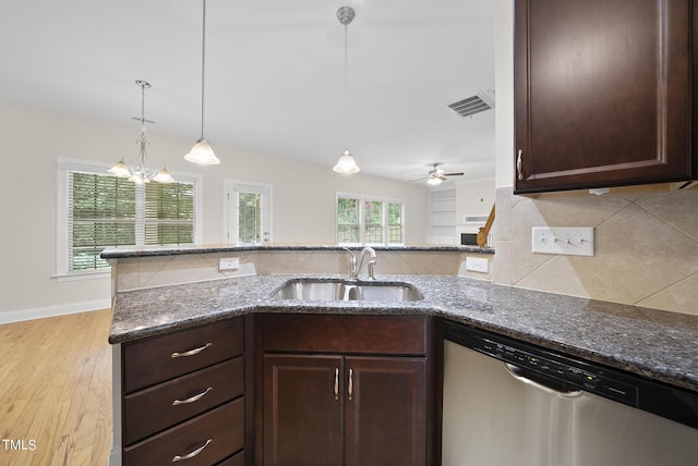 kitchen featuring visible vents, a sink, stainless steel dishwasher, backsplash, and dark stone counters