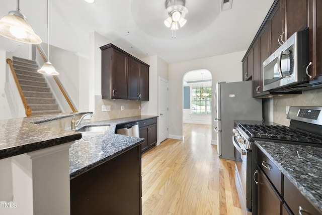 kitchen with visible vents, dark brown cabinetry, dark stone counters, stainless steel appliances, and a sink