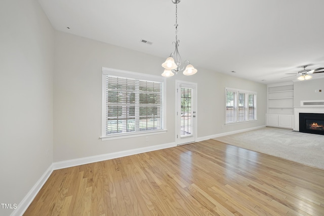 unfurnished living room with built in features, visible vents, a fireplace with flush hearth, and light wood-style floors