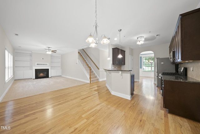 kitchen with dark brown cabinetry, a breakfast bar area, a fireplace with flush hearth, and appliances with stainless steel finishes