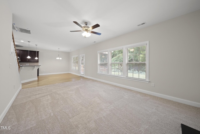 unfurnished living room with visible vents, light colored carpet, and ceiling fan