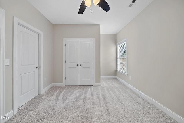 unfurnished bedroom with visible vents, light carpet, a closet, baseboards, and ceiling fan