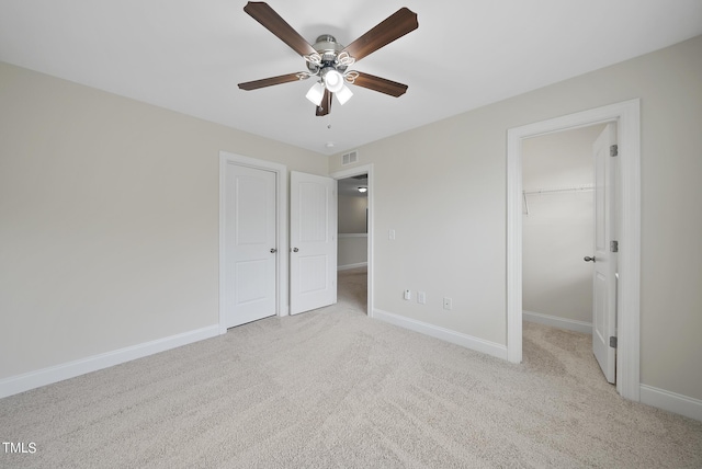 unfurnished bedroom featuring a walk in closet, baseboards, carpet, and visible vents