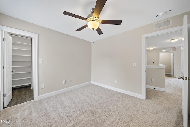 unfurnished bedroom with a walk in closet, carpet, visible vents, and baseboards