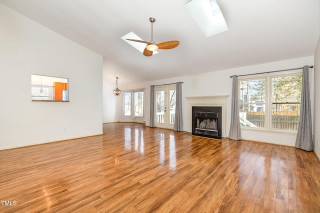 unfurnished living room with ceiling fan, plenty of natural light, light hardwood / wood-style flooring, and a skylight