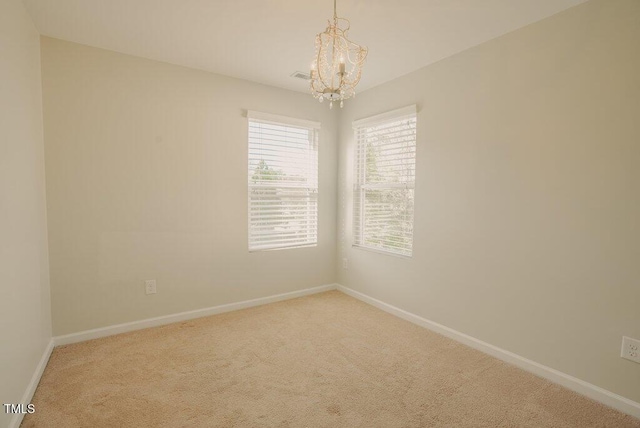 spare room featuring carpet flooring and a notable chandelier