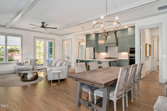 dining space featuring beam ceiling, light wood-type flooring, french doors, and ceiling fan with notable chandelier