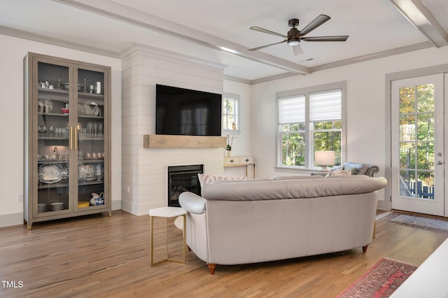 living room with a fireplace, beam ceiling, ceiling fan, and wood-type flooring