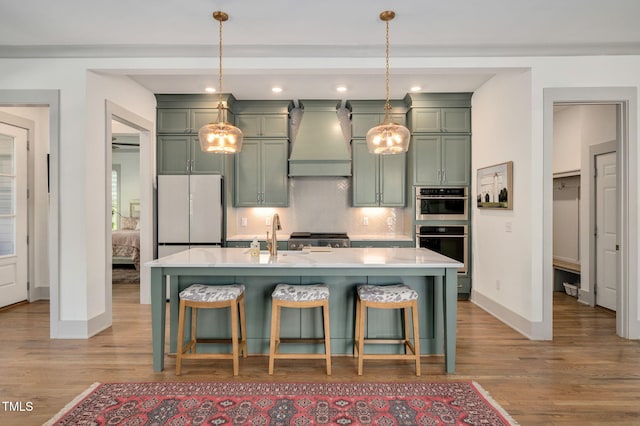 kitchen featuring custom exhaust hood, hanging light fixtures, white fridge, a breakfast bar, and tasteful backsplash