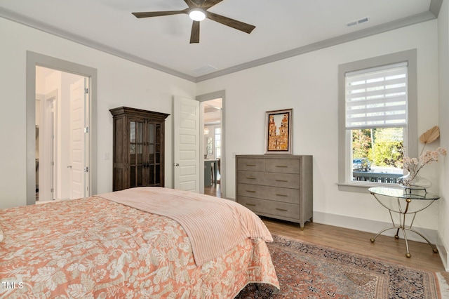 bedroom with hardwood / wood-style floors, ceiling fan, and ornamental molding