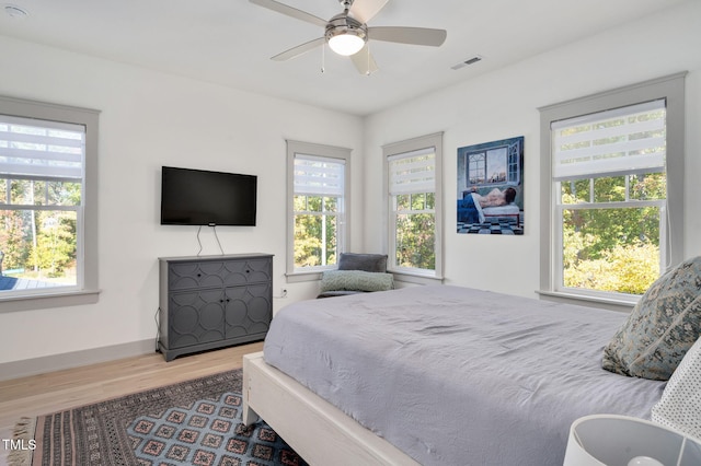 bedroom with ceiling fan, hardwood / wood-style floors, and multiple windows