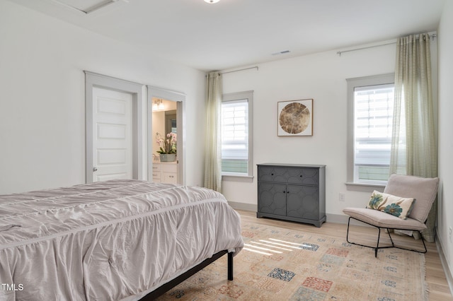 bedroom featuring light hardwood / wood-style flooring and connected bathroom